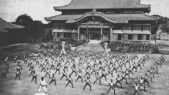 The martial art of karate was born on Okinawa and this black and white scene is a training session in front of Shuri Castle